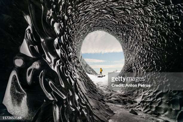 man exploring an amazing glacial cave in iceland - vinden stockfoto's en -beelden