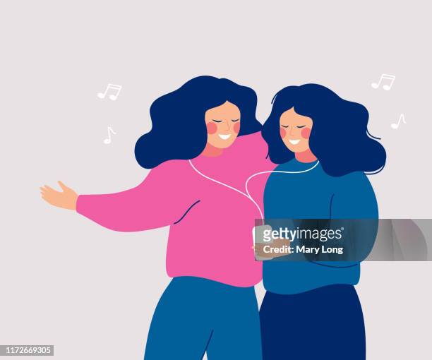 Young cheerful women sharing their earphone and listening to music with mobile phone and dancing.