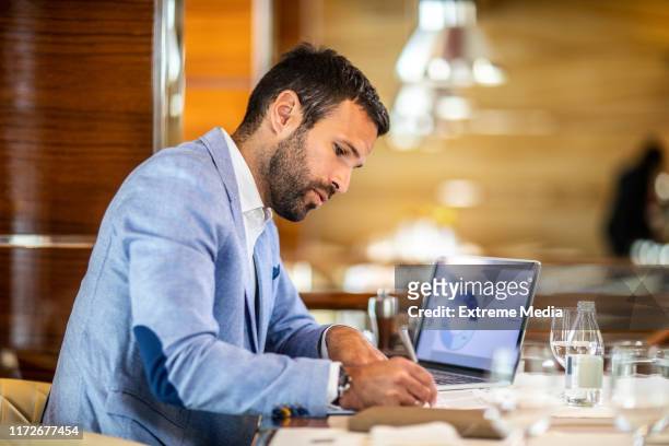ondernemer schrijven op een document tijdens het zitten in een restaurant - risico stockfoto's en -beelden