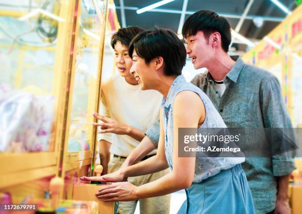 friends playing arcade claw machine - claw machine game stock pictures, royalty-free photos & images