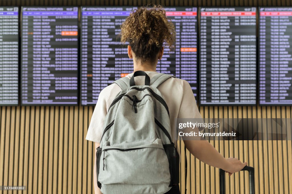 Giovane viaggiatrice che guarda le informazioni di volo