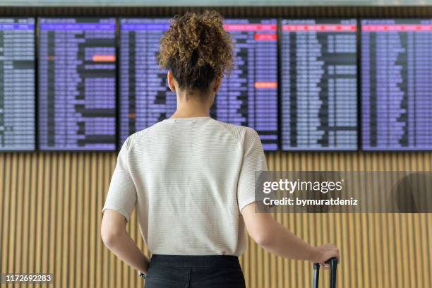 junge reiseleiterin schaut sich fluginformationen an - passagierflugzeug stock-fotos und bilder