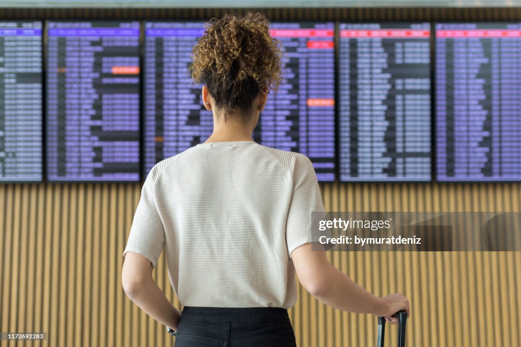 Young woman traveler looking at flight information