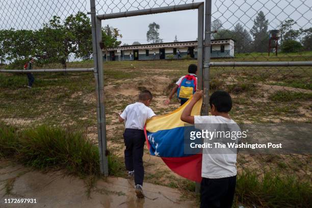 Children carry the Venezuelan national flag at the beginning of the school day in the small town of Parai-Tepui, Venezuela on May 15, 2019. The...