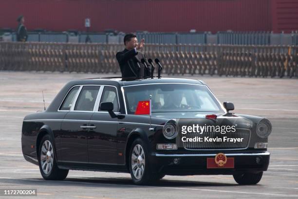 Chinese President Xi Jinping waves as he drives after inspecting the troops during a parade to celebrate the 70th Anniversary of the founding of the...