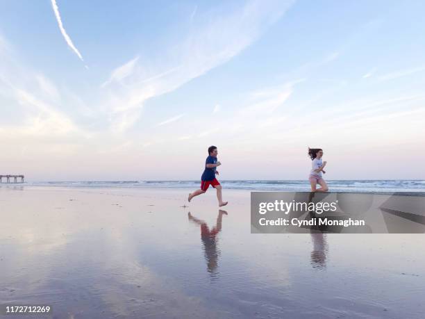 siblings running on a wide empty beach - beach florida family stockfoto's en -beelden
