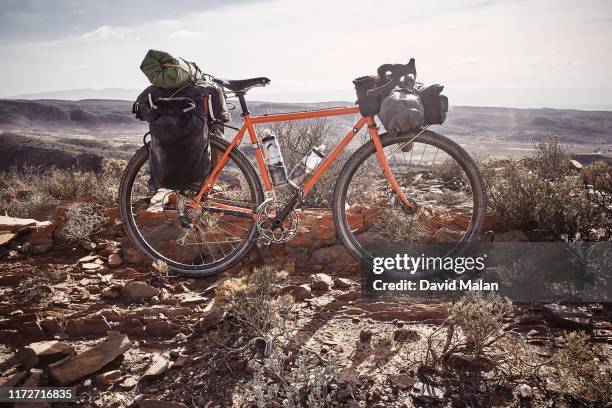 an orange adventure bicycle, loaded with panniers and bike-packing bags for touring, in a remote desert landscape. - panier stock-fotos und bilder