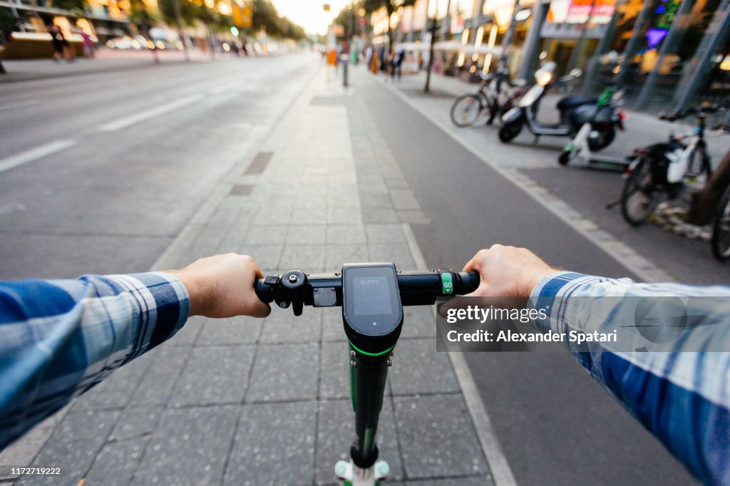 Riding electric scooter in the city, personal perspective view