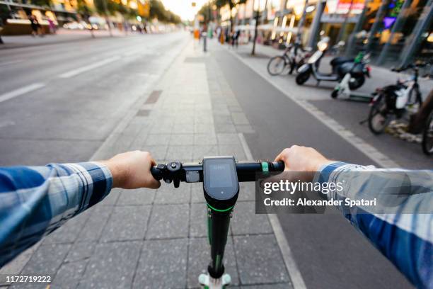 riding electric scooter in the city, personal perspective view - lambreta imagens e fotografias de stock
