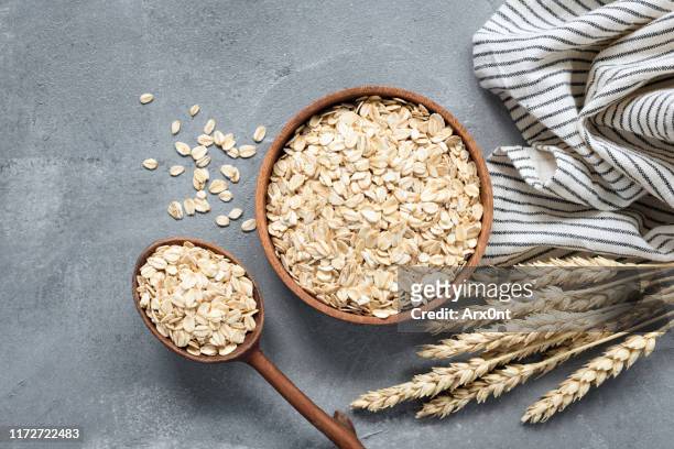 oats, rolled oats or oat flakes in wooden bowl - fiocchi di avena foto e immagini stock
