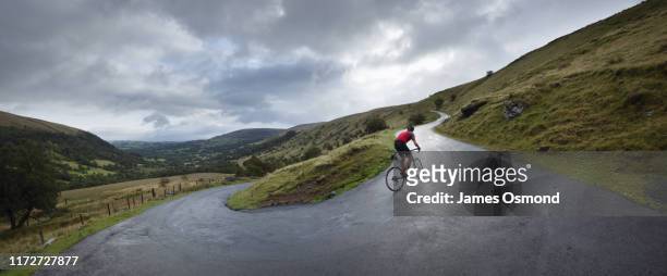 road cyclist climbing hairpin bends up hillside. - hairpin curve stock-fotos und bilder