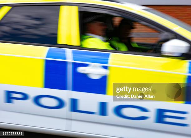 two police officers sitting in car driving at speed on the road - police car stock pictures, royalty-free photos & images