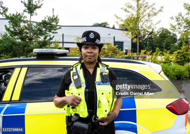 portrait of traffic cop standing by the side of police car - police uk stock pictures, royalty-free photos & images