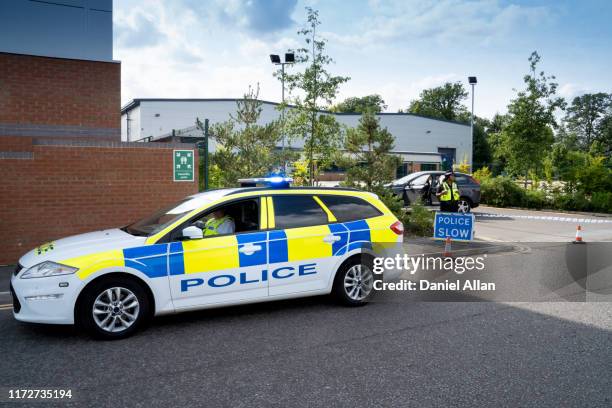 police officer sitting in police car at the side of the road with policewoman in bacground - police car stock pictures, royalty-free photos & images