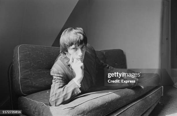 English drummer Mick Avory of rock band The Kinks lounging on a sofa, UK, 21st May 1965.