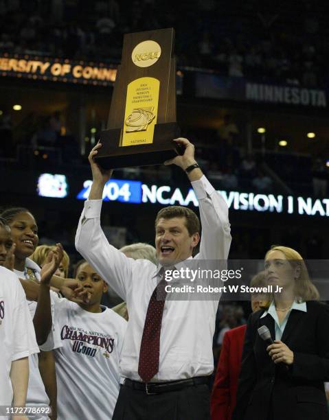 University of Connecticut women's basketball coach Geno Auriemma holds the trophy above his head after his team defeated Tennessee to win the 2004...