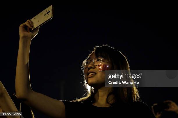 Girl uses iphone take pictures of fireworks during a massive parade to celebrate the 70th anniversary of the founding of the People's Republic of...