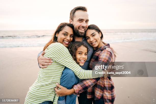 große familie umarmung - hispanic man on beach stock-fotos und bilder