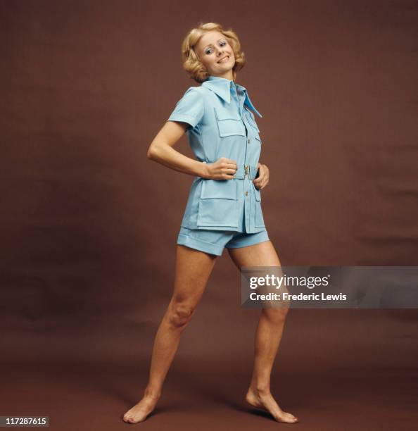 Woman modelling women's fashions in a studio portrait, wearing a two-piece outfit comprising of a light blue short-sleeved blouse and matching...