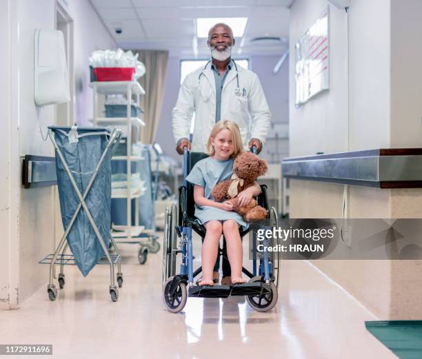 smiling doctor with girl on wheelchair in hospital - childrens hospital stock pictures, royalty-free photos & images