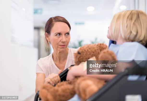 mother looking at girl on wheelchair in hospital - children's hospital stock pictures, royalty-free photos & images