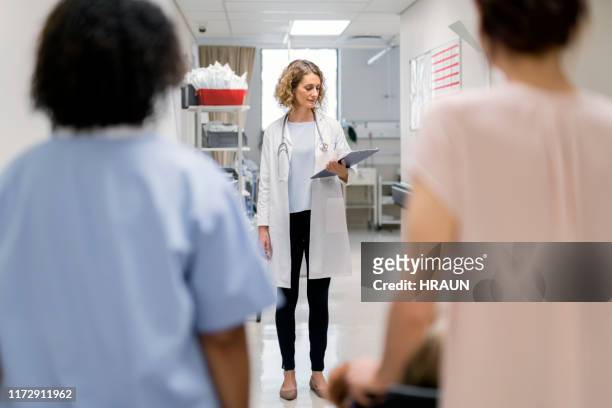 nurse and woman standing in front of female doctor - children's hospital stock pictures, royalty-free photos & images