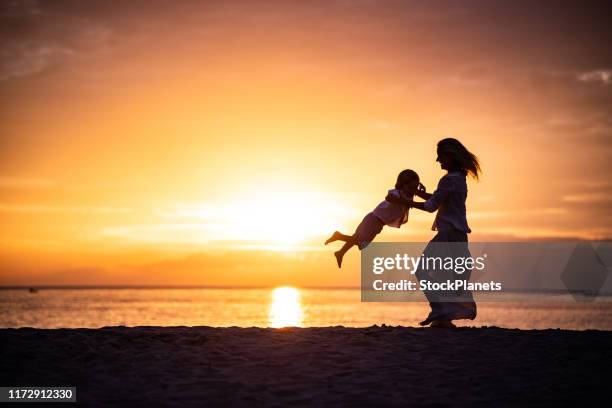 junge mutter rotierenden sohn bei sonnenuntergang - silhouettes boys showing with finger stock-fotos und bilder