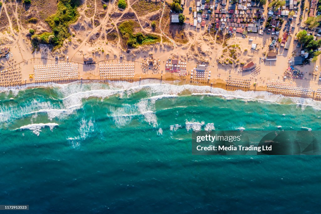 Aerial drone view of a crowded beach umbrellas bars and people on the summer sand