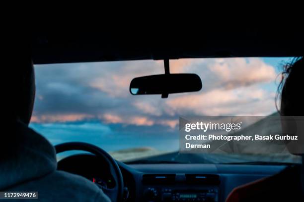 rear view of two unrecognizable people on the road, in a car - car rear view mirror stock pictures, royalty-free photos & images