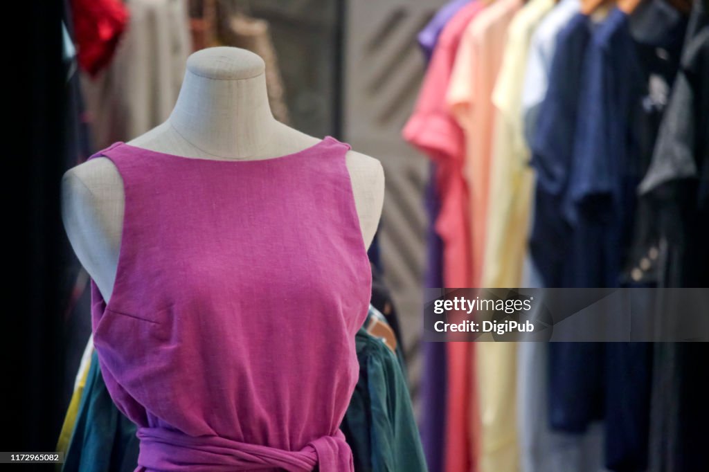 Female like torso in pink casual dress against clothes hanging