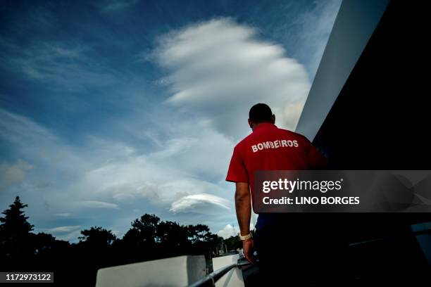 Firefighter looks at heavy clouds in Madalena, on the Pico Island, on October 1, 2019 as Hurricane Lorenzo passes over the Portuguese archipelago of...