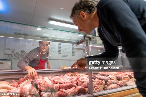 cliente maschio che punta a un pezzo di carne da macellare - butcher foto e immagini stock