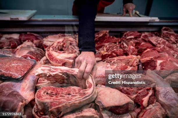 varietà di carne fresca presso la macelleria e uomo irriconoscibile afferrando un pezzo - butcher foto e immagini stock