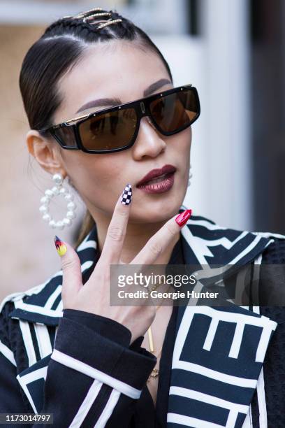 Patricia Gunawan with double braid with leather detail, flame detail nail paint, sunglasses and over sized pearl drop hoop earrings during New York...