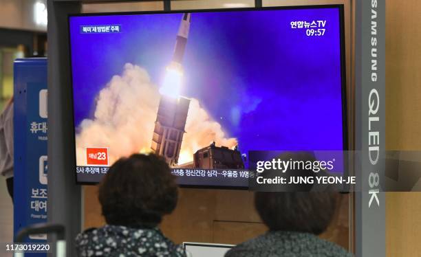 People watch a television news screen showing file footage of a North Korean missile launch, at a railway station in Seoul on October 2, 2019. North...