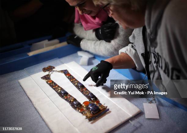 Jackie Hoff , museum consultant and collections manager, examines a gold inlaid pectoral, chain, and counterpoise with Lapis scarab flanked by Uraei,...