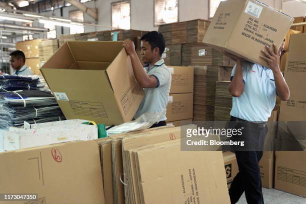 Worker carries a box of clothing, right, as other workers pack at the Sri Rejeki Isman PT factory in Solo, Central Java, Indonesia, on Friday, Sept....