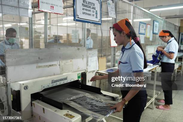 Worker places a piece of packed clothing onto a metal detector machine at the Sri Rejeki Isman PT factory in Solo, Central Java, Indonesia, on...