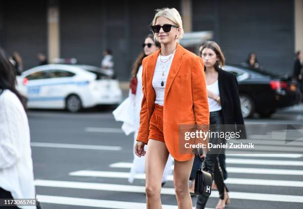 Caroline Daur is seen wearing an orange jacket, white top and orange shorts and black bag outside the R13 show during New York Fashion Week S/S20 on...
