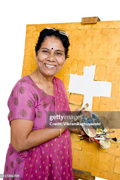 eine farbenfrohe indische senior frau künstler arbeiten an ihrem gemälde - jesus is alive stock-fotos und bilder