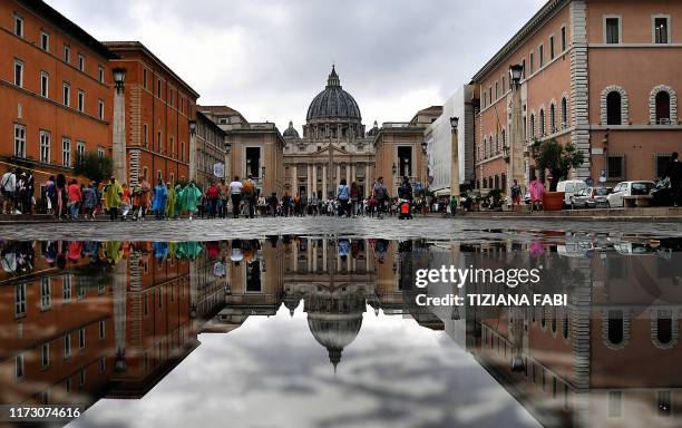 This photo taken from Via della Conciliazione in Rome on October 2, 2019 shows the Vatican's St. Peter's Basilica reflected in a puddle following...