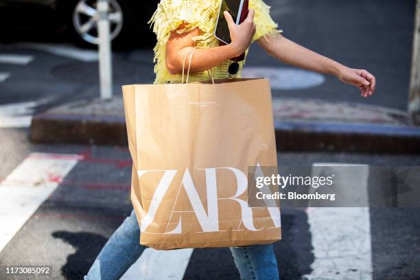 Pedestrian carries a shopping bag from a Zara fashion store, operated by Industria de Diseno Textil SA, while walking along a street in New York,...