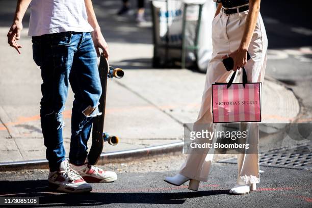 Pedestrian carries a Victoria's Secret Stores LLC shopping bag while waiting to cross a street in New York, U.S., on Wednesday, Sept. 25, 2019....