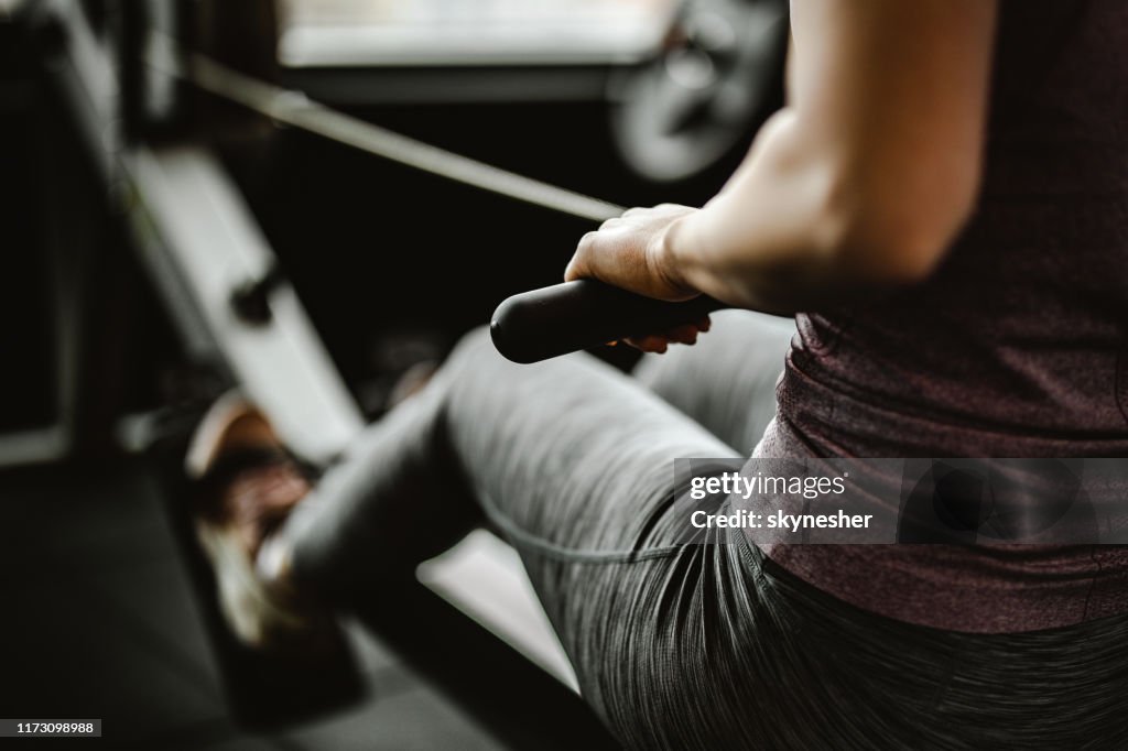 Nahaufnahme von nicht wiederzuerkennenden Frauen, die auf rudernden Geräten in einem Fitnessstudio trainieren.