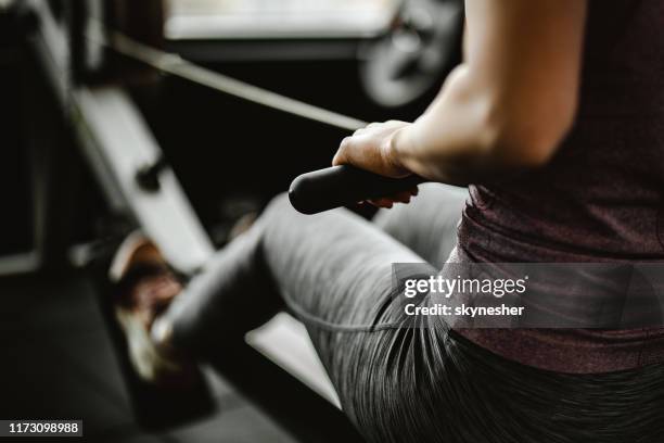 närbild av oigenkännlig kvinna som tränar på roddmaskin i ett gym. - träna bildbanksfoton och bilder