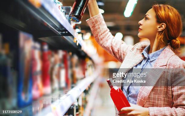 buying alcohol at supermarket. - wine shelf stock pictures, royalty-free photos & images