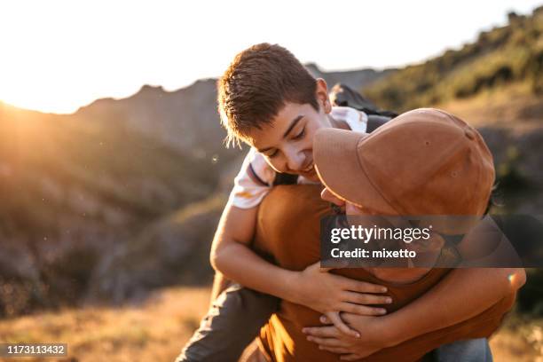 piggyback in mountains is always great idea - teen son stock pictures, royalty-free photos & images