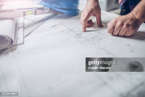 hands of engineer working on blueprint - construction meeting helmet stock pictures, royalty-free photos & images