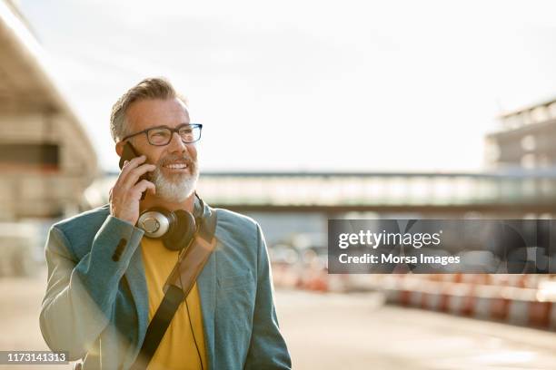 mature businessman talking on mobile phone in city - street clear sky stock pictures, royalty-free photos & images