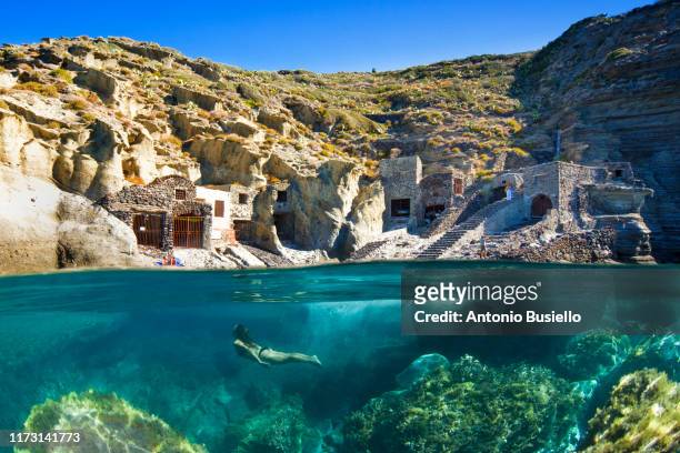 young woman swimming underwater with pollara old fishing boat shed in surface - italian island photos et images de collection